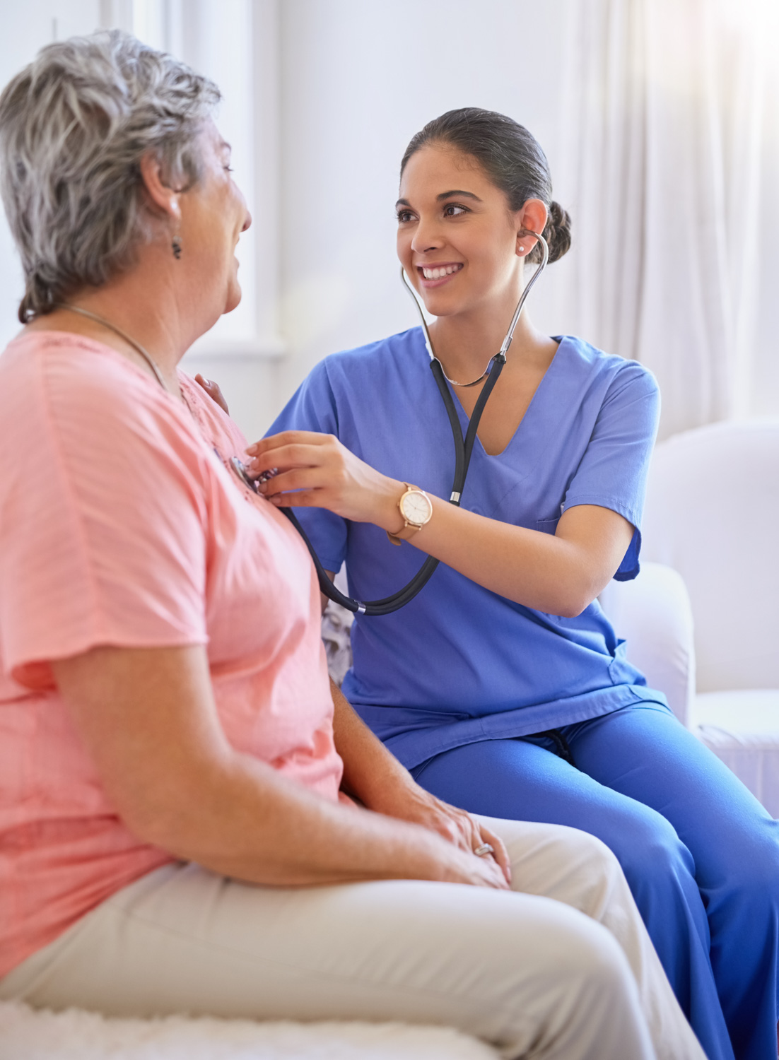 female nurse listening to elderly woman's heartbeat