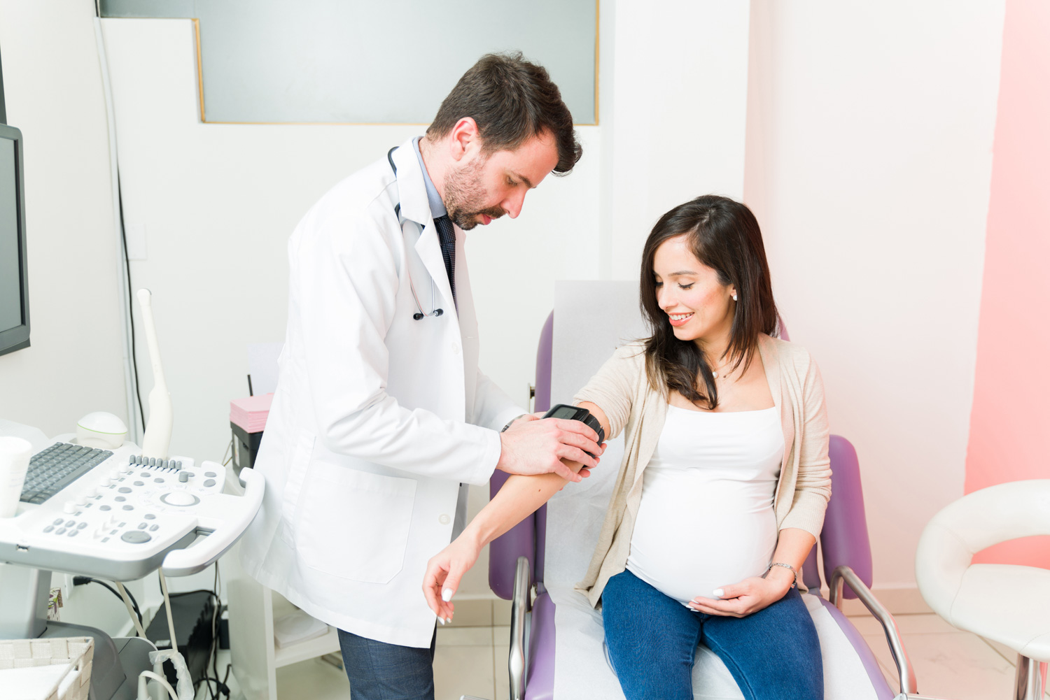 male gynecologist taking blood pressure from pregnant woman
