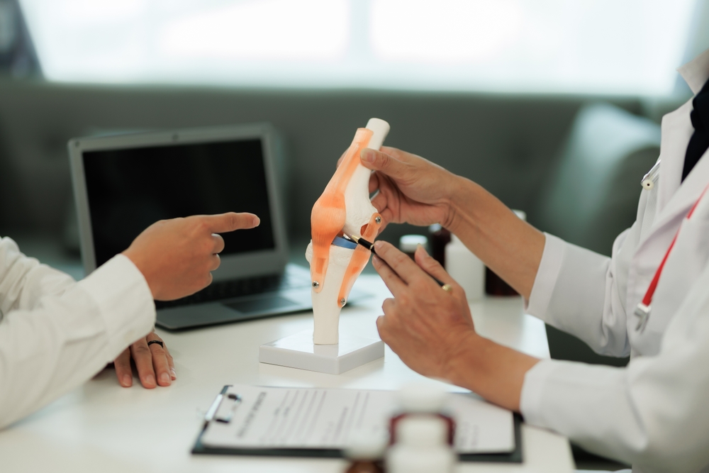 Doctor showing knee anatomical model