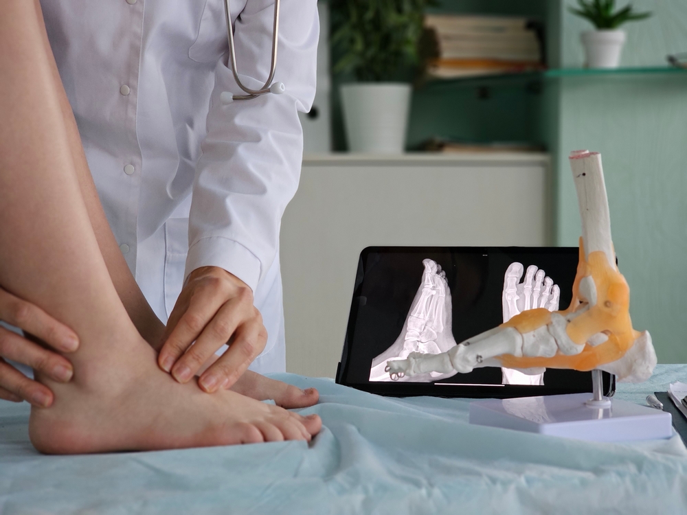 doctor assessing ankle beside foot anatomical model