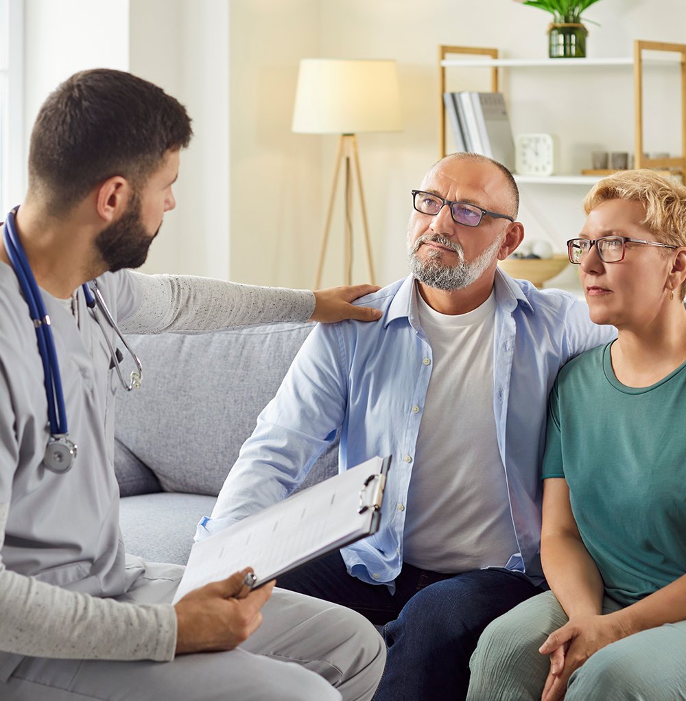 Male Doctor Talking to Middle Aged Couple During a Sick Visit