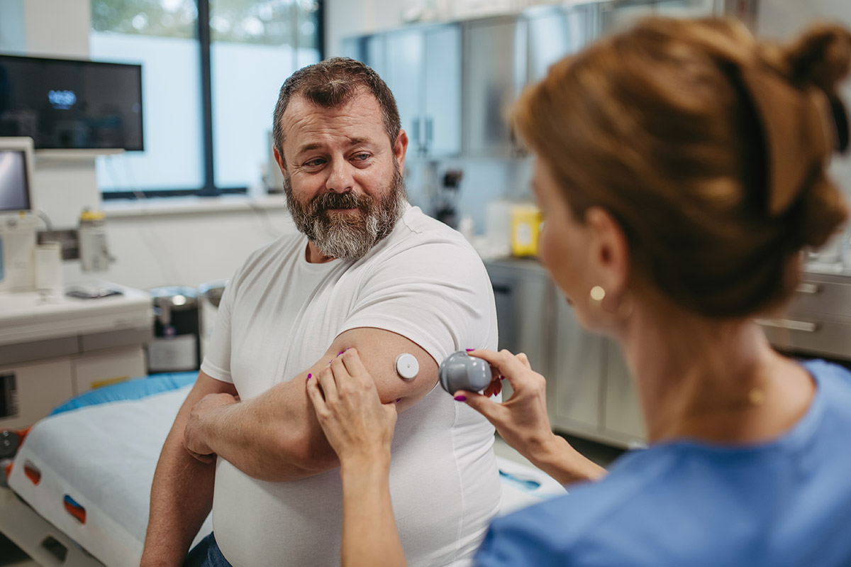 Doctor applying a continuous glucose monitor sensor on a patient's arm at Townsen Physician Group in Houston