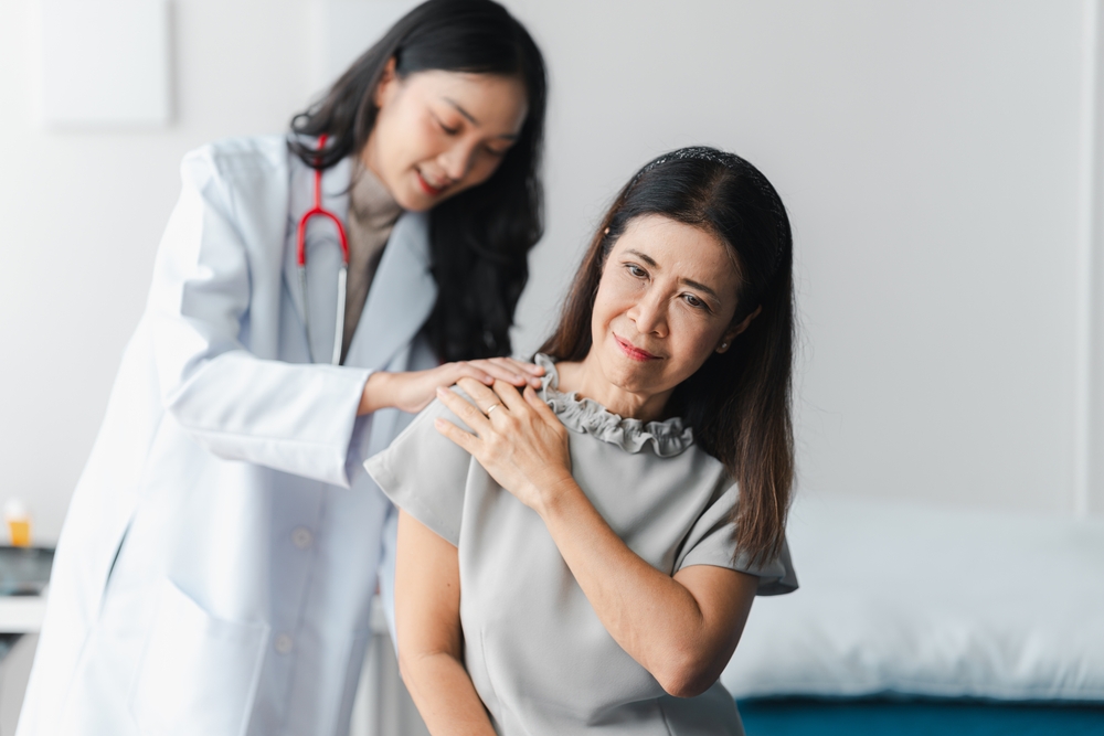 female doctor checking female patient's shoulder 