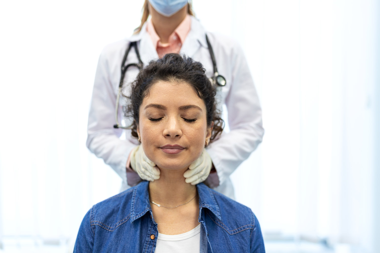 Doctor examining a female patient's neck at Townsen Physician Group in Houston