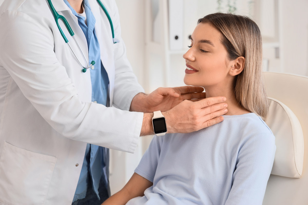 Male doctor checking a female patient's thyroid at Townsen Physician Group in Houston