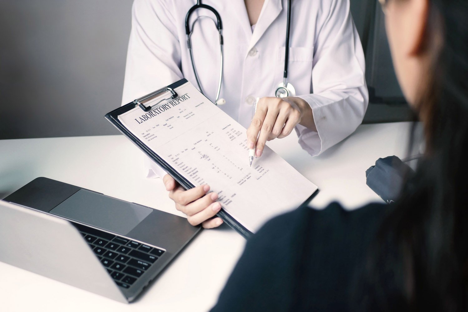 doctor holding clipboard explaining results to patient