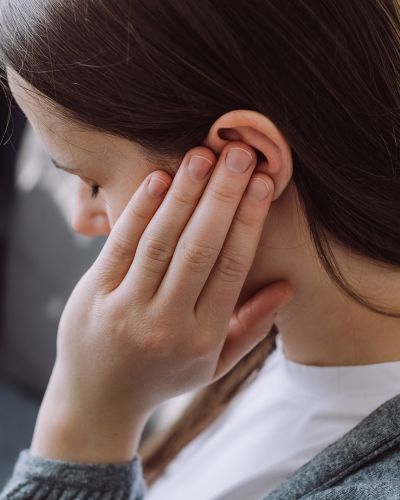 Young Woman with Tinnitus Touching Ear with Hand